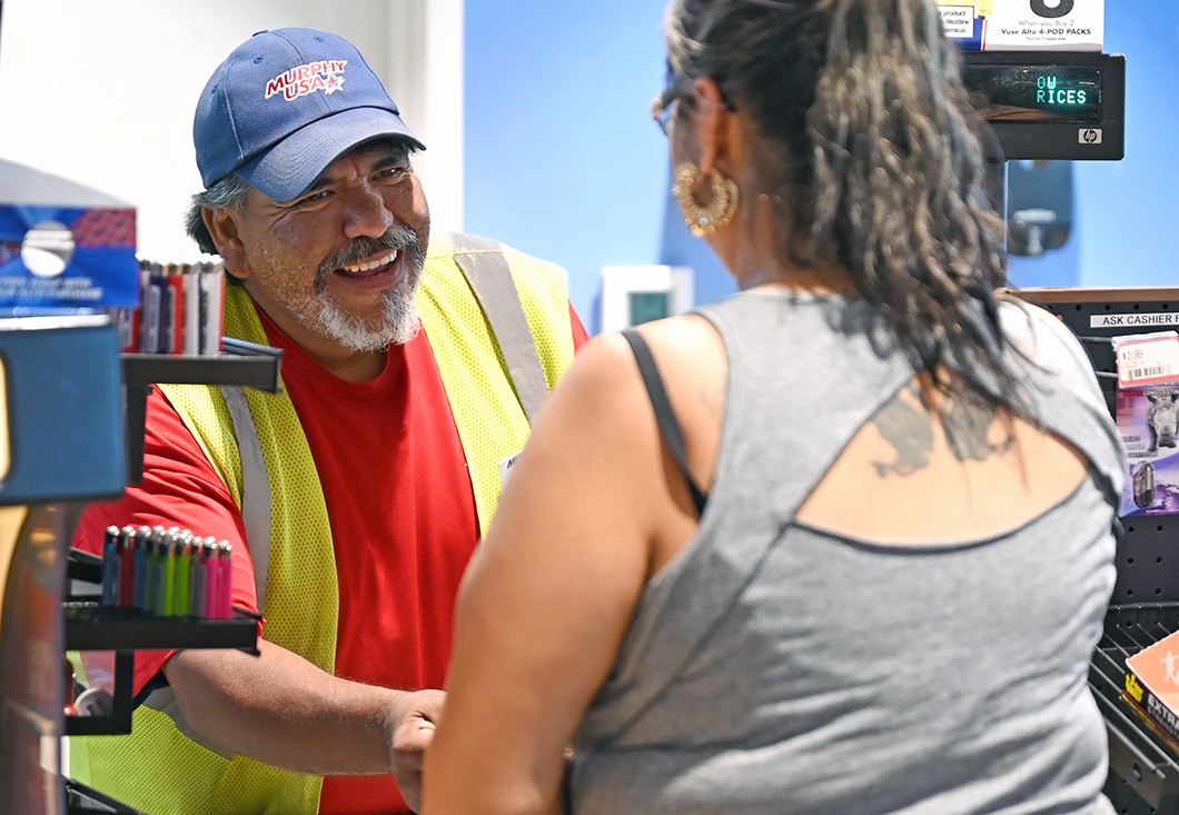 An employee helped with job training programs assists a customer at his new job.